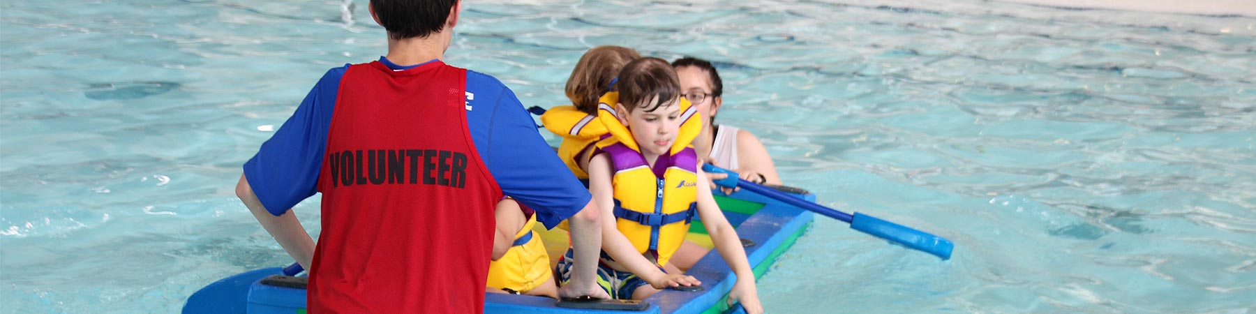 Photo of aquatics volunteer in the pool with young kids having fun